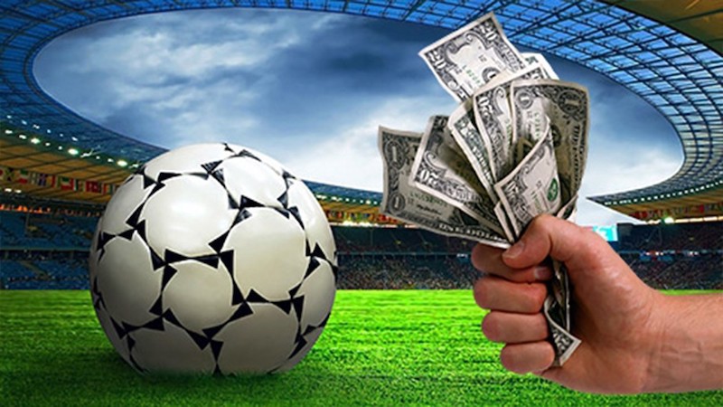 A football on a football pitch with a hand holding money.