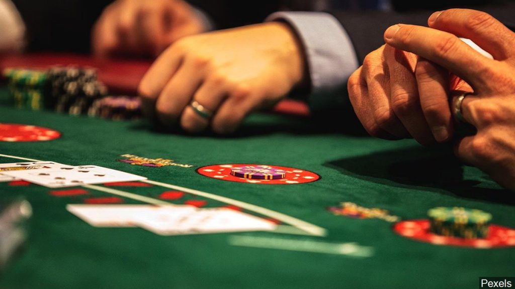 Mens hands at a Blackjack table with cards and poker chips. 