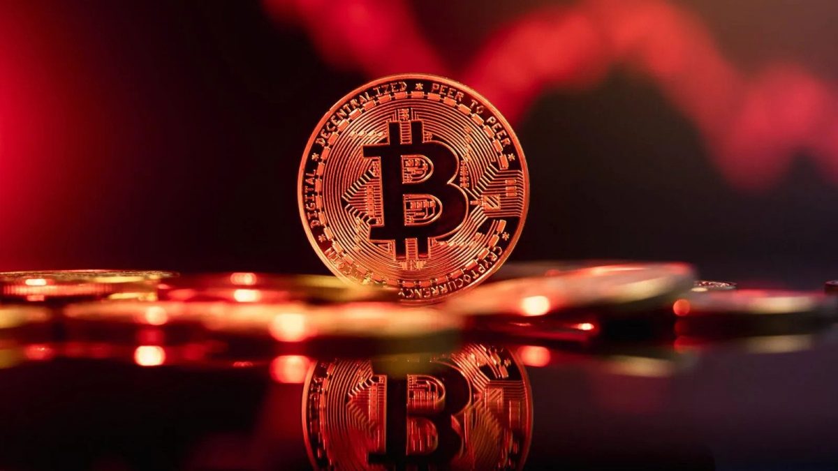 um Bitcoin em uma mesa com moedas de ouro com fundo vermelho