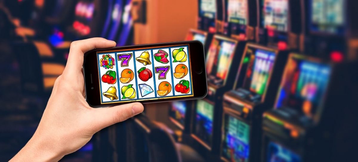 Hand holding a phone with a Casino Games Online and slot machines in the background